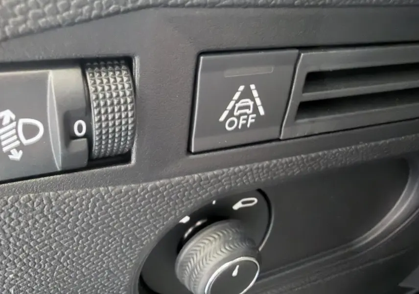 Gros plan sur le tableau de bord du DS3 Crossback 2022, bouton d'alerte franchissement de ligne et réglage des phares.