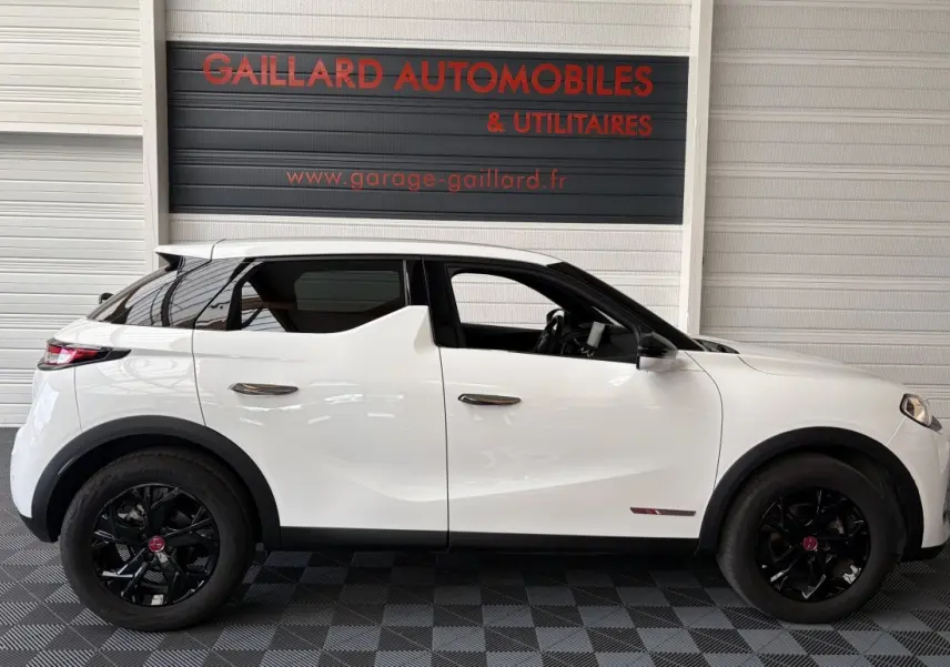 Vue de profil côté gauche d'un DS3 Crossback blanc avec jantes noires et rétroviseurs ton caisse dans un garage.