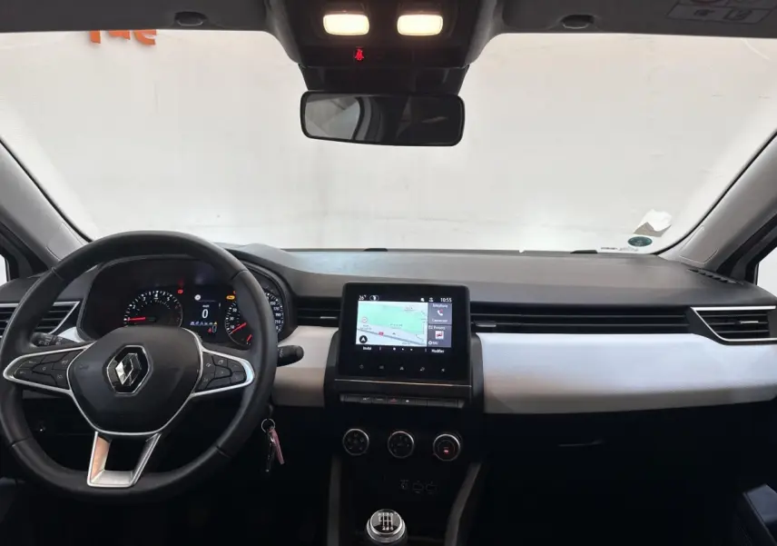 Vue intérieure avant de la Renault Clio blanche 2023, avec tableau de bord moderne et écran tactile central.