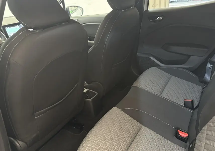 Vue intérieure arrière de la Renault Clio blanche 2023, montrant la banquette tissu bicolore et les dossiers des sièges avant.