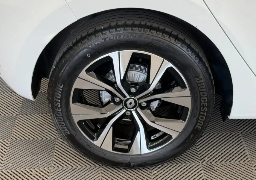 Gros plan sur la roue avant droite d'une Renault Clio blanche, jante alliage bicolore avec logo Renault central.