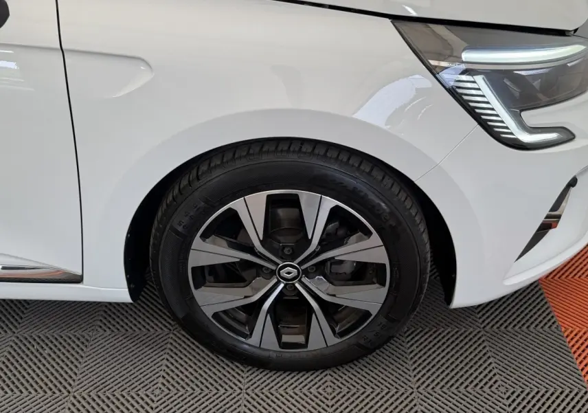Gros plan sur la roue avant gauche et le phare LED d'une Renault Clio blanche Evolution TCe 100 GPL 2023.