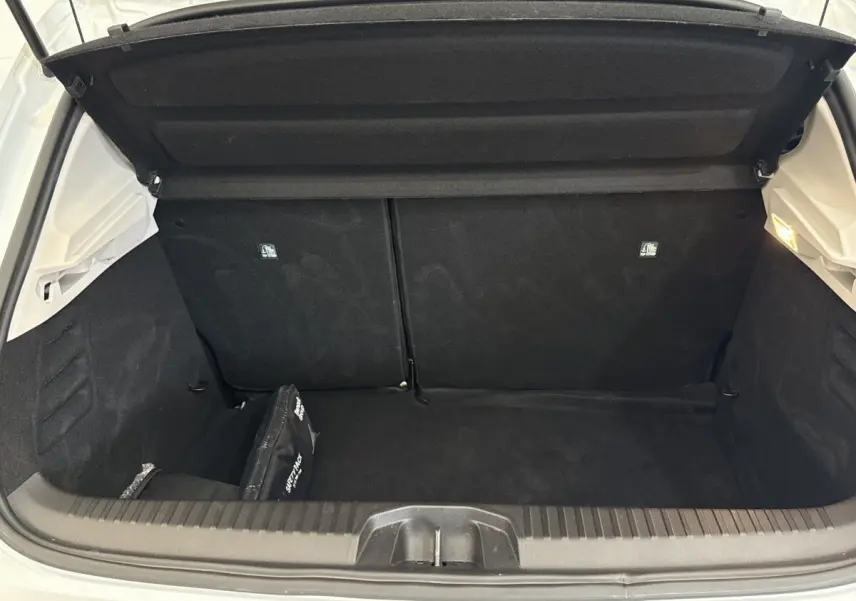 Coffre ouvert vu de l'arrière d'une Renault Clio blanche 2023, intérieur noir avec trousse de secours.