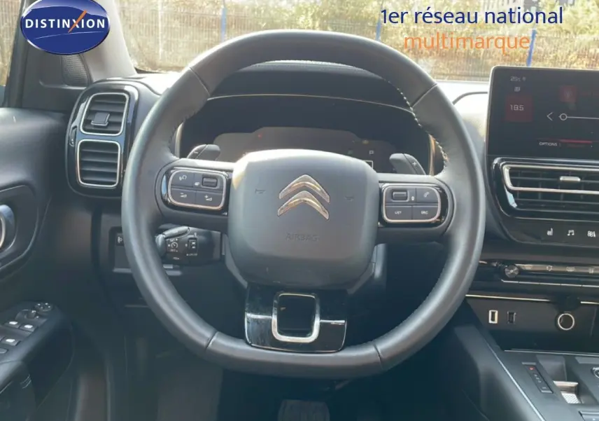 Vue intérieure centrée sur le volant cuir noir du Citroën C5 Aircross 2025 avec tableau de bord et écran tactile.