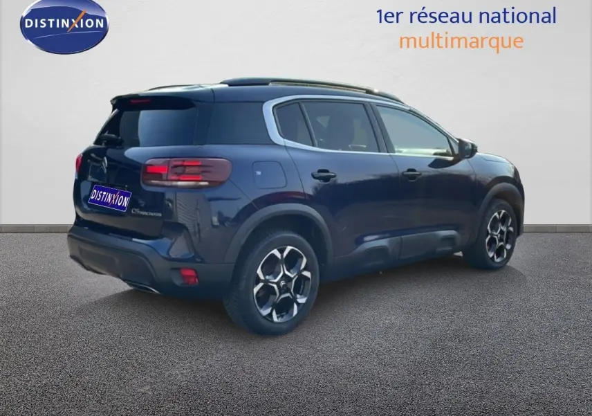 Vue 3/4 arrière droite d'un Citroën C5 Aircross bleu Eclipse Metal avec jantes bi-ton et toit noir.