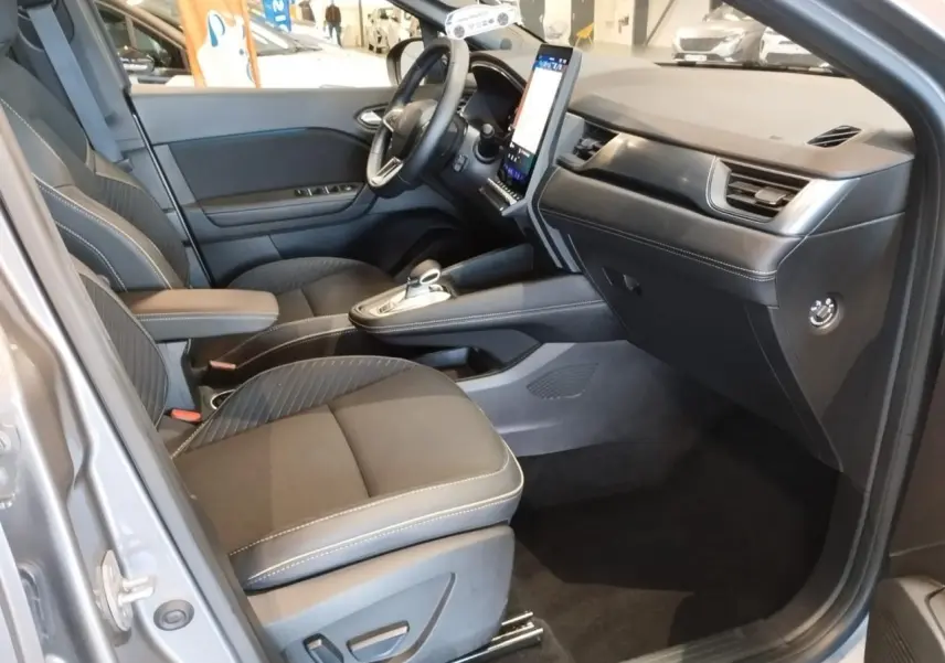 Intérieur avant droit du Renault Symbioz gris Cassiopée, sièges tissu noir et console centrale avec écran vertical tactile.