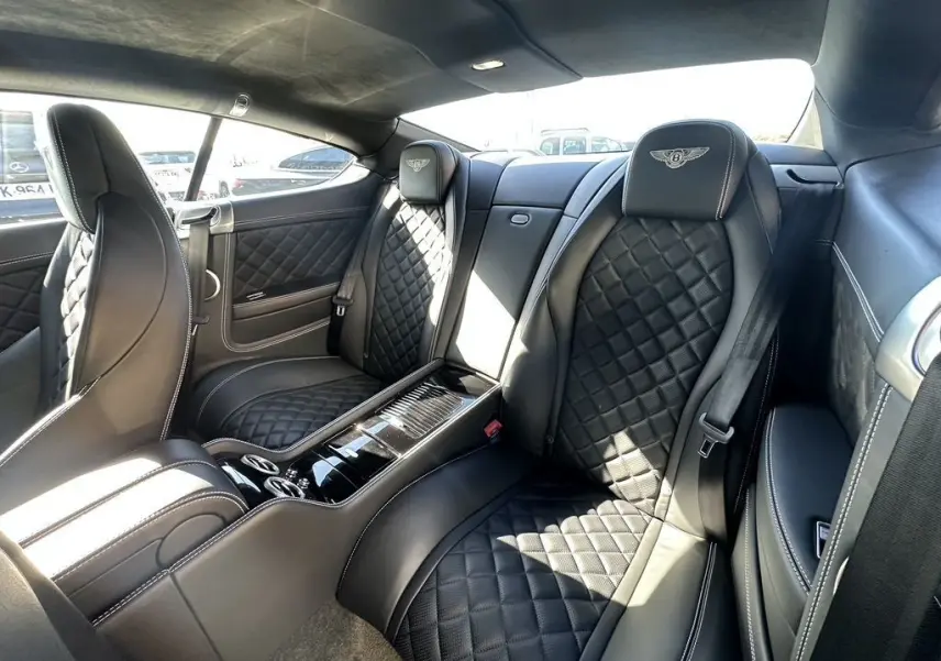 Vue intérieure arrière droite du Bentley Continental GT Speed 2015 noire, sièges en cuir matelassé avec logo Bentley brodé.