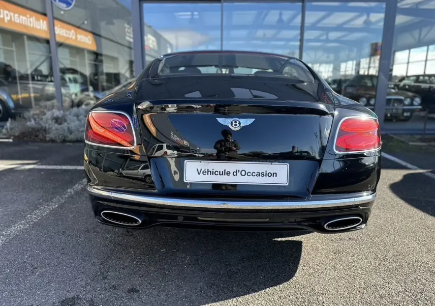 Vue arrière d'une Bentley Continental GT Speed noire de 2015, avec feux rouges et double sortie d'échappement chromée.