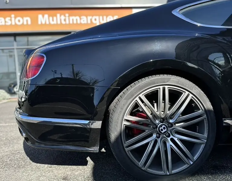 Vue latérale arrière droite d'une Bentley Continental GT Speed noire avec jante alliage et étrier de frein rouge visible.