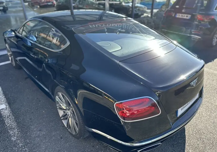 Vue 3/4 arrière droite d'une Bentley Continental GT Speed noire de 2015 avec feux arrière rouges et jantes alliage.