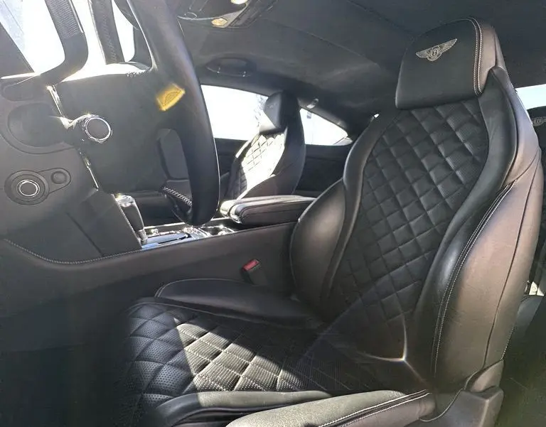 Intérieur noir de la Bentley Continental GT II, vue côté conducteur mettant en valeur les sièges en cuir matelassé avec logo brodé.