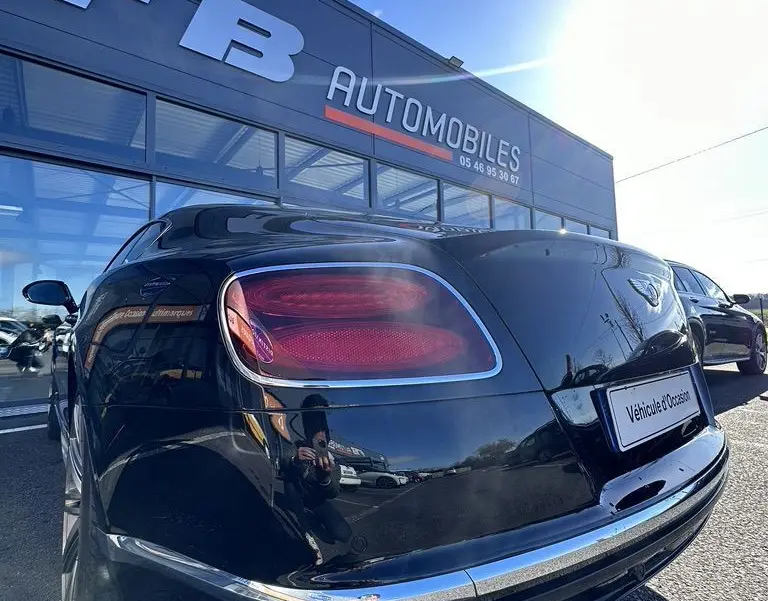 Vue 3/4 arrière droite d'une Bentley Continental GT Speed noire 2015 avec feux arrière ovales et double sortie d'échappement chrome.