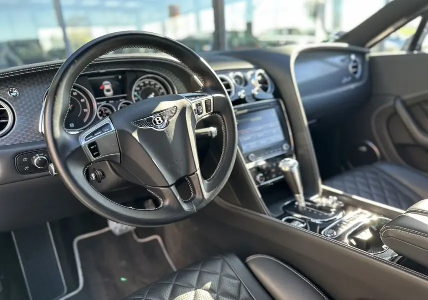 Intérieur noir de la Bentley Continental GT Speed 2015, vue du poste de conduite avec volant et console centrale en cuir.