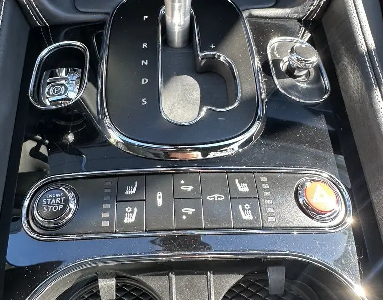 Gros plan sur la console centrale noire de la Bentley Continental GT Speed 2015 avec levier de vitesses automatique et boutons de contrôle.
