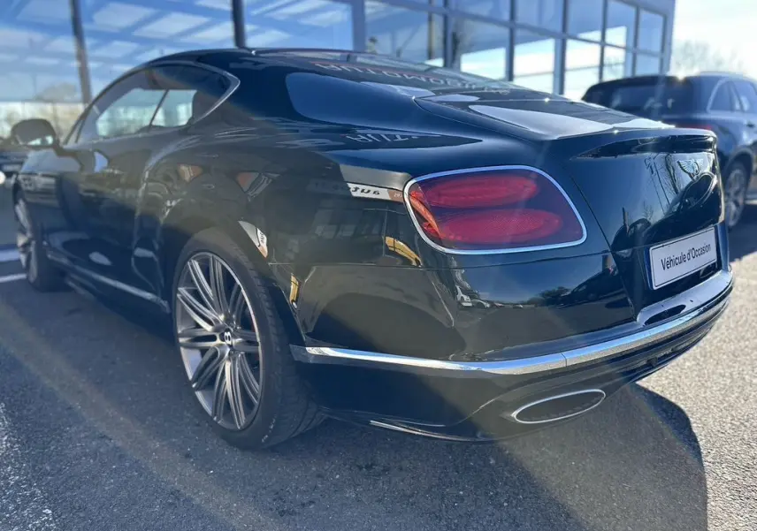 Bentley Continental GT Speed noire vue 3/4 arrière droit, avec feux rouges et jantes alliage distinctives.