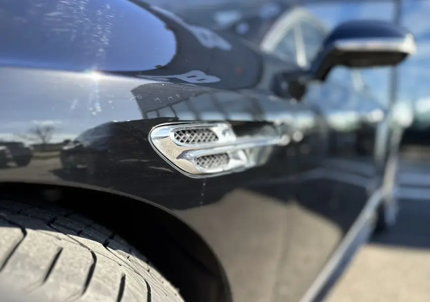 Détail de la prise d'air chromée sur l'aile avant gauche d'une Bentley Continental GT Speed noire 2015.
