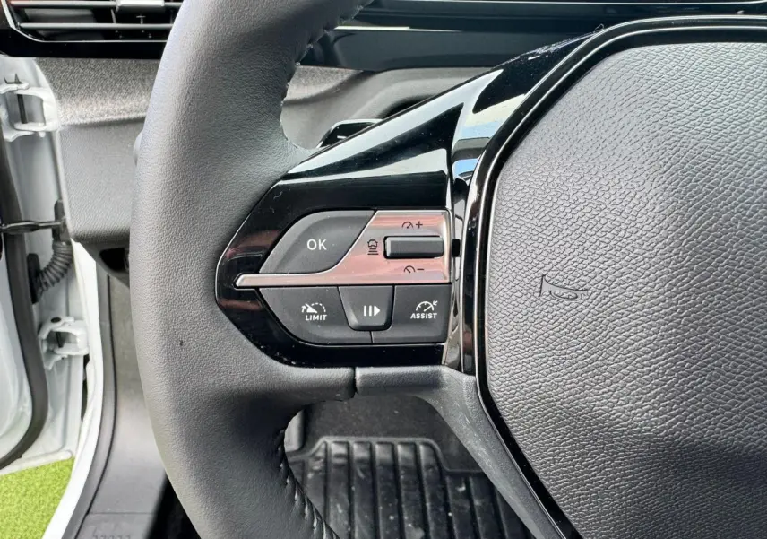 Gros plan sur le volant noir du Peugeot 308 SW 2024, montrant les commandes de régulateur et assistant de conduite.