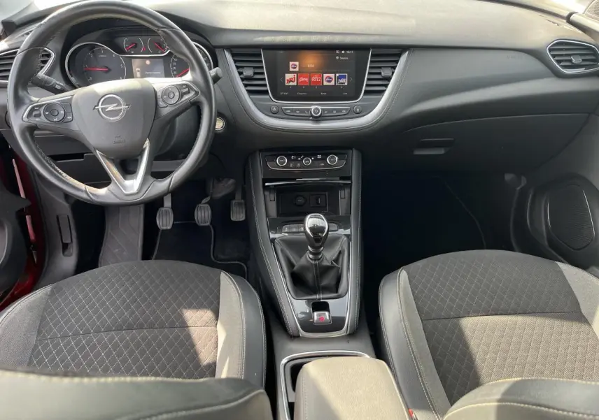 Vue intérieure avant de l'Opel Grandland rouge 2018, volant cuir, boîte manuelle, écran tactile et sièges tissu noir.