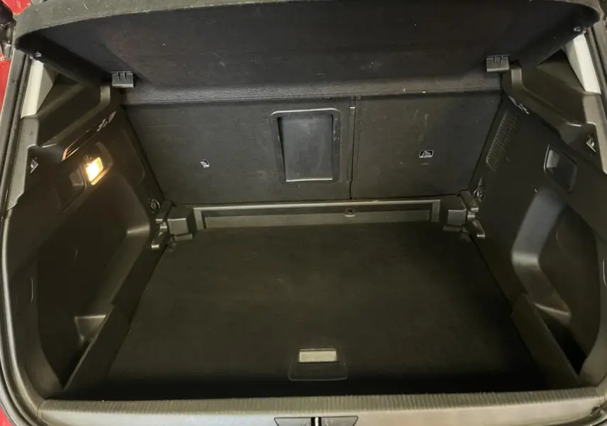 Coffre ouvert vu de l'arrière d'un Opel Grandland rouge 2018, espace de chargement noir et éclairage intérieur allumé.
