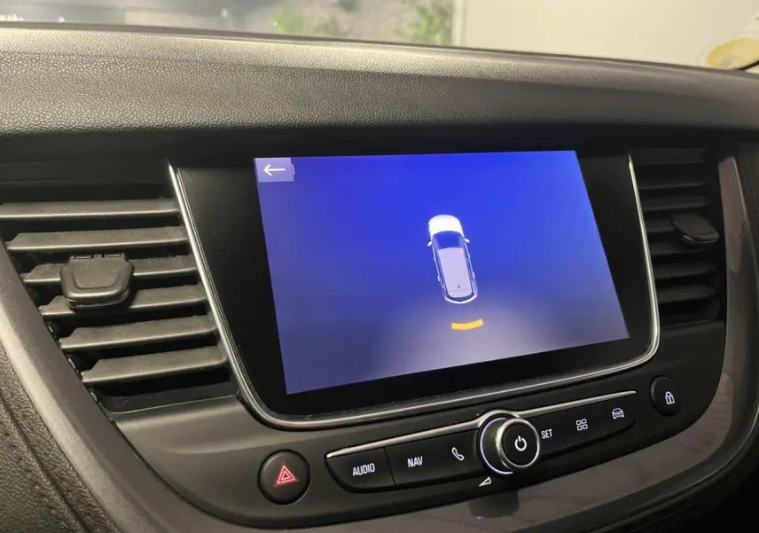 Écran tactile central du tableau de bord de l'Opel Grandland rouge, affichant l'aide au stationnement.