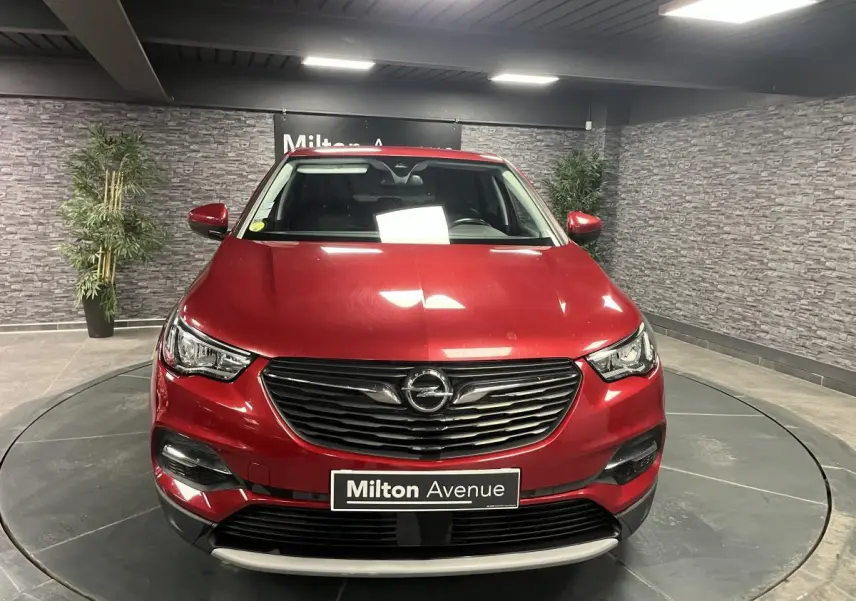 Opel Grandland rouge métallisé vue de face en intérieur avec calandre noire et plaque Milton Avenue.