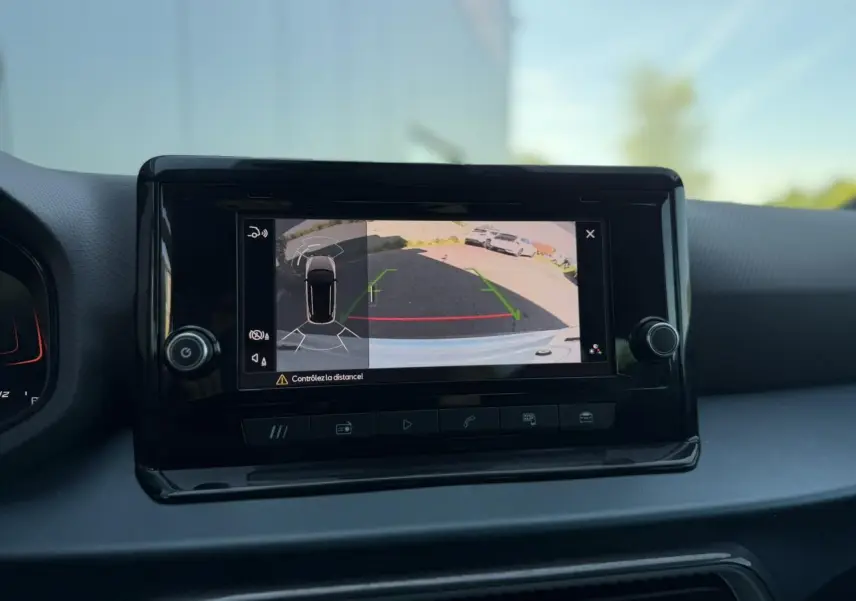 Écran central montrant la caméra de recul et l’aide au stationnement du SEAT Arona blanc Nevada, vue intérieure.