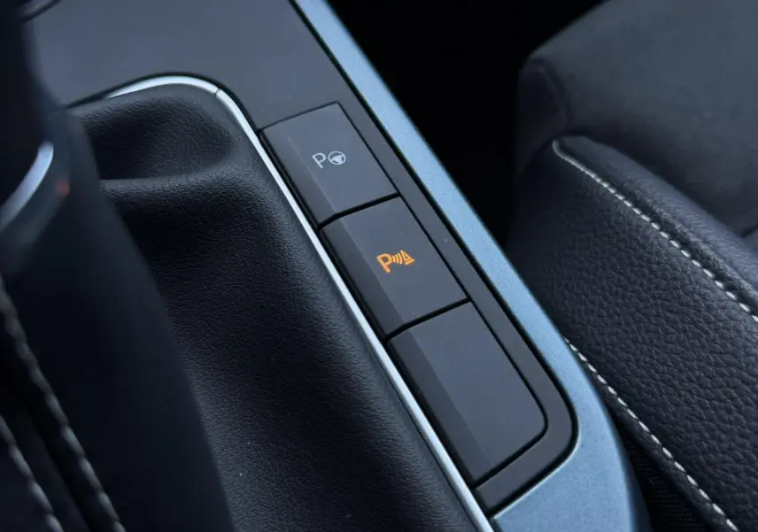 Gros plan sur les boutons d’assistance au stationnement dans l’habitacle noir du SEAT Arona TSI 115 Xpérience.