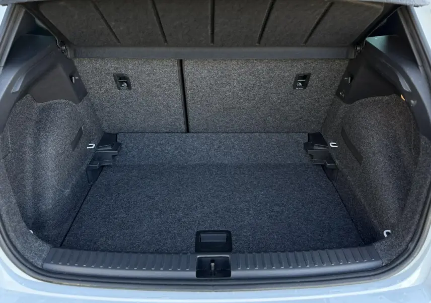 Coffre ouvert vu de l'arrière d'un SEAT Arona blanc Nevada, montrant un espace de chargement vide et doublé de moquette grise.