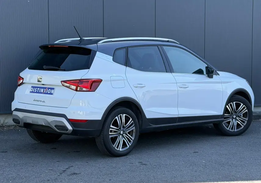 Vue 3/4 arrière droite du SEAT Arona blanc Nevada avec toit noir et jantes alliage 17 pouces, arrière surteinté.