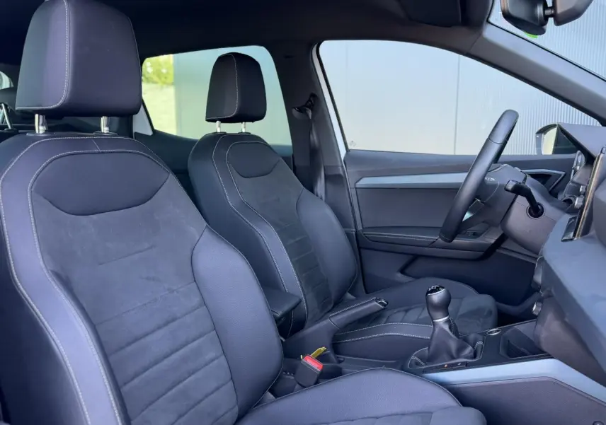Intérieur côté conducteur du SEAT Arona TSI 115 Xpérience 2025, sièges cuir-alcantara noirs avec surpiqûres blanches.
