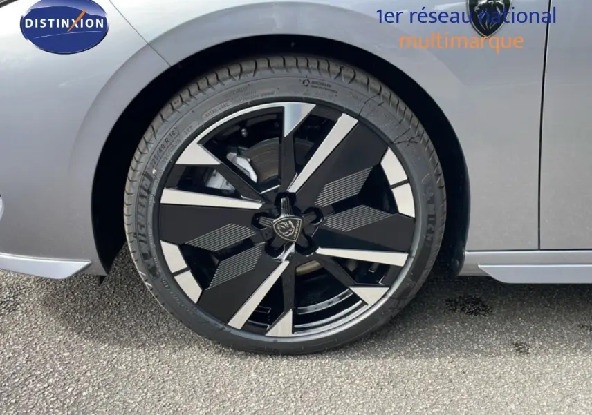 Gros plan sur la roue avant gauche d’une Peugeot 308 gris Artense métal avec jante noire et argentée au design moderne.