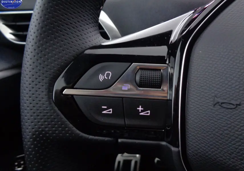 Gros plan sur les commandes gauche du volant perforé d’un Peugeot 3008 GT 2023 noir Perla Nera Metal.