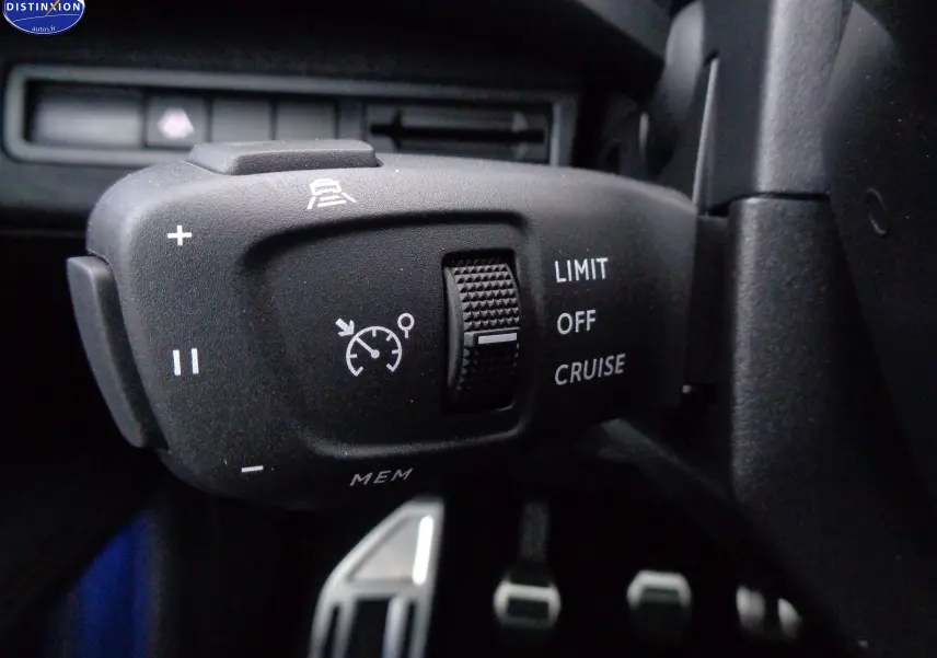 Gros plan sur la commande de régulateur de vitesse du Peugeot 3008 noir Perla Nera, avec molette et symboles blancs.