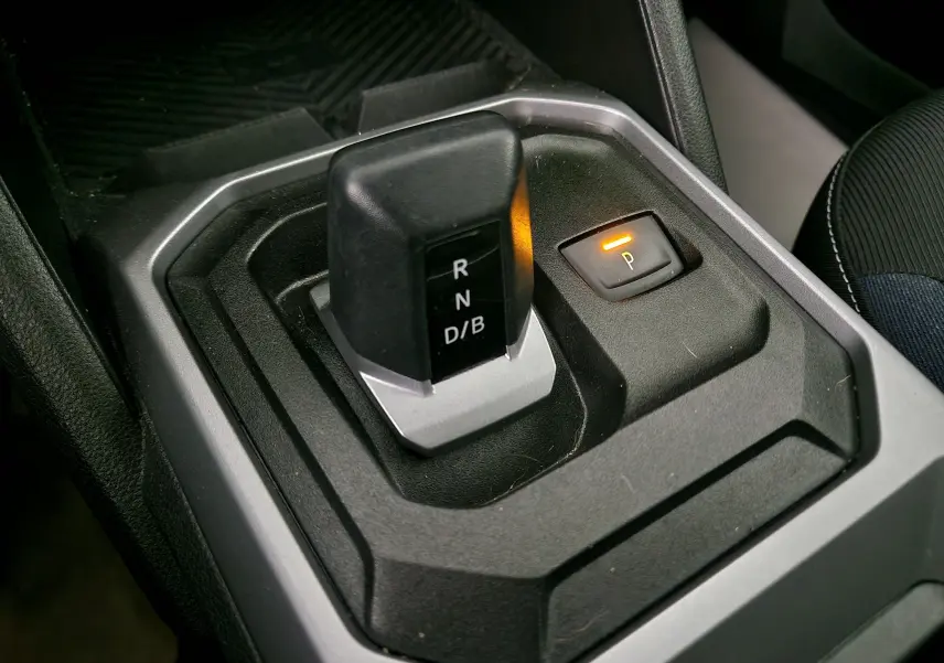 Gros plan sur le levier de vitesses automatique noir du Dacia Duster 2024 avec bouton de parking éclairé en orange.