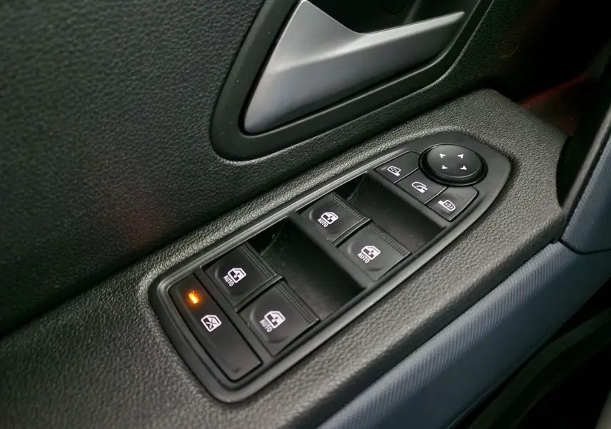 Gros plan sur les commandes des vitres électriques côté conducteur du Dacia Duster 2024 noir, avec bouton de verrouillage activé.