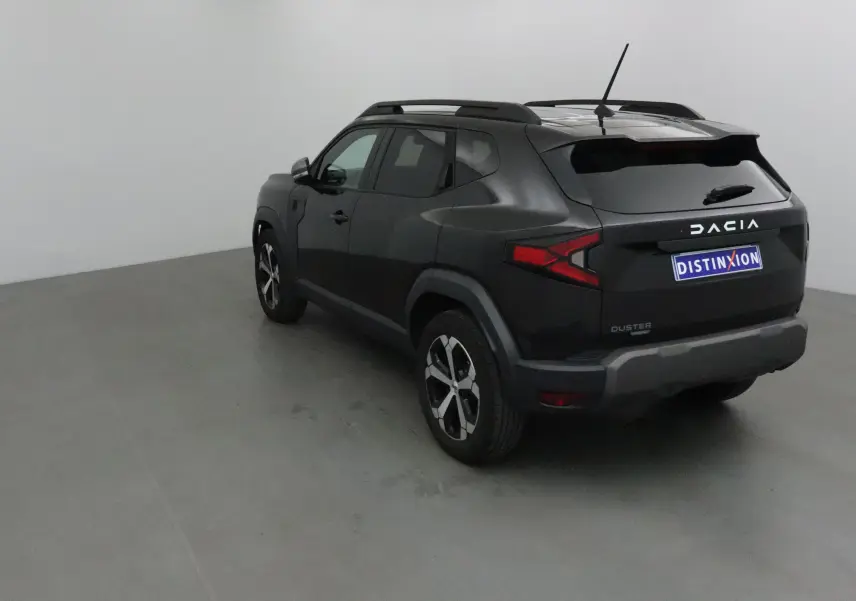 Vue 3/4 arrière droite du Dacia Duster noir 2024 avec feux arrière en forme de flèche et jantes alliage bicolores.