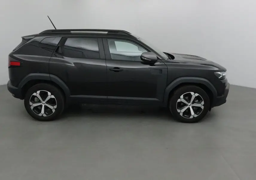 Profil côté gauche du Dacia Duster 2024 noir, version hybride 4x2 avec lignes anguleuses et toit noir contrastant.