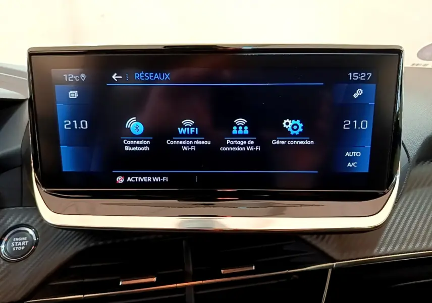 Écran tactile central affichant les options réseau dans l'habitacle d'une Peugeot 208 gris clair, vue frontale rapprochée.