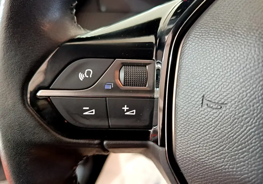 Gros plan sur les commandes du volant cuir noir de la Peugeot 208 PureTech 100 S&S Allure Business 2020.