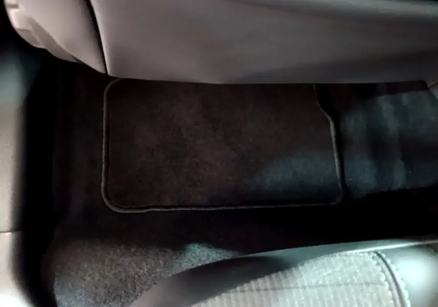 Vue rapprochée du tapis de sol noir sous le siège arrière d'une Peugeot 208 gris clair de 2020