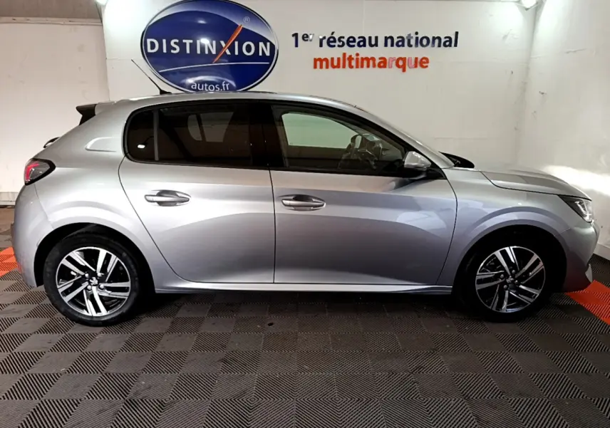 Profil côté droit d'une Peugeot 208 gris clair 2020 PureTech 100 S&S Allure Business en intérieur showroom.
