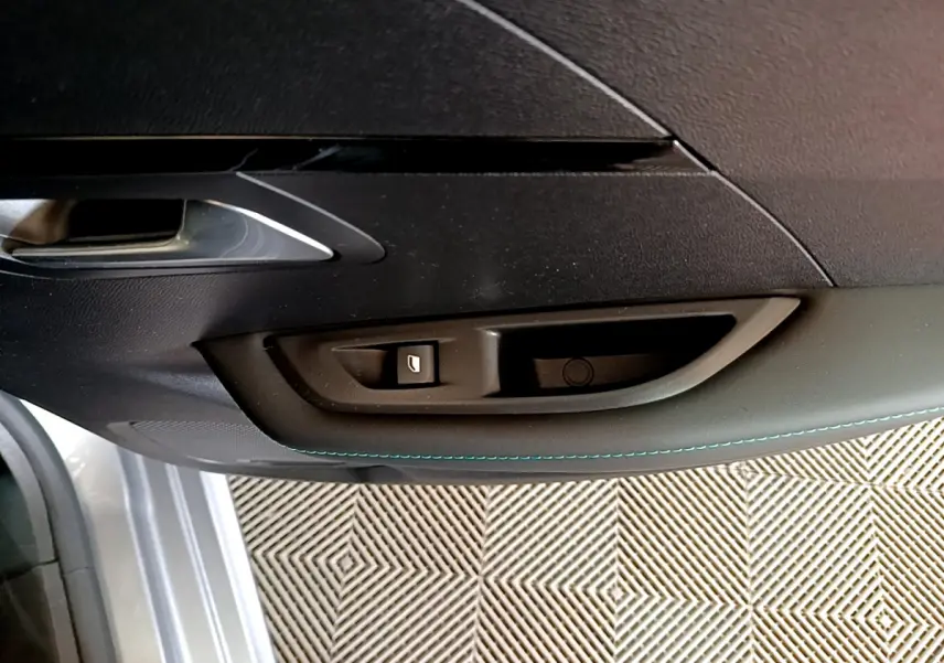 Gros plan sur la poignée intérieure et commande de lève-vitre côté conducteur d'une Peugeot 208 gris clair 2020.