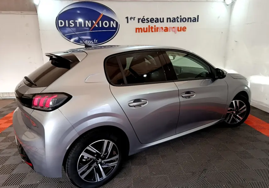 Peugeot 208 gris clair vue 3/4 arrière droit, feux arrière LED et jantes alliage distinctives visibles.
