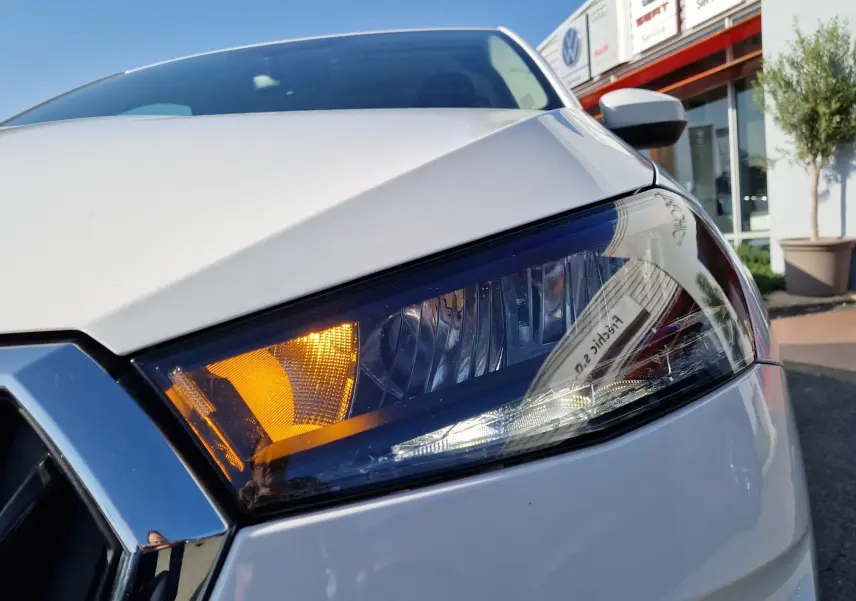Gros plan sur le phare avant droit blanc d'une Skoda Fabia Berline Active 2022 avec clignotant allumé.