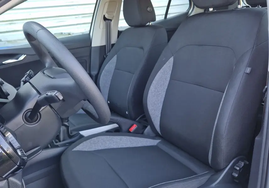 Vue intérieure côté gauche de la Skoda Fabia Berline Active 2022 blanche, montrant les sièges avant en tissu noir et gris.