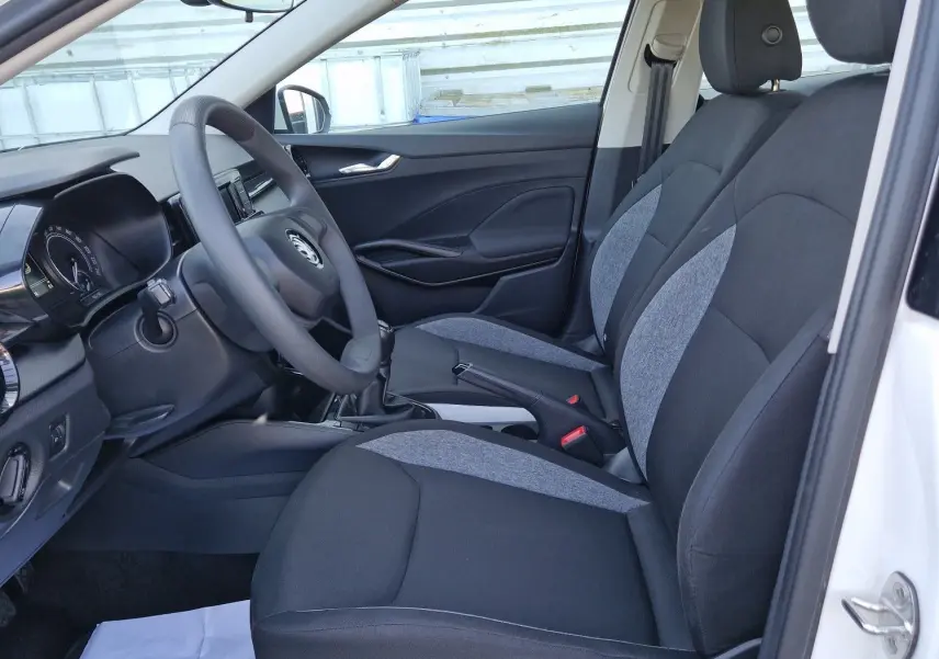 Vue intérieure côté conducteur de la Skoda Fabia Berline Active blanche 2022, sièges tissu noir et gris, volant et tableau de bord visibles.