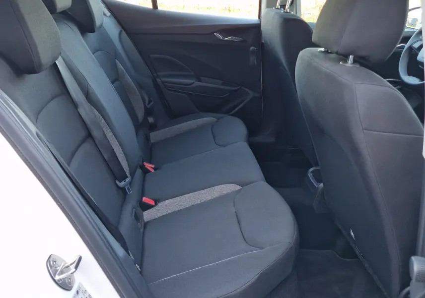 Vue intérieure côté arrière gauche de la Skoda Fabia berline blanche 2022, montrant les sièges arrière en tissu noir.