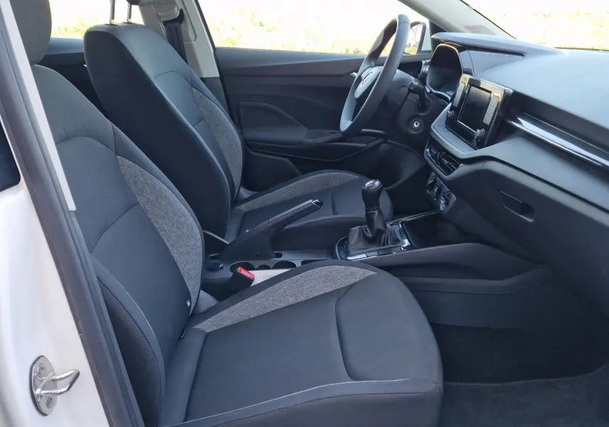 Intérieur côté conducteur d'une Skoda Fabia blanche 2022, avec sièges tissu gris et console centrale manuelle.
