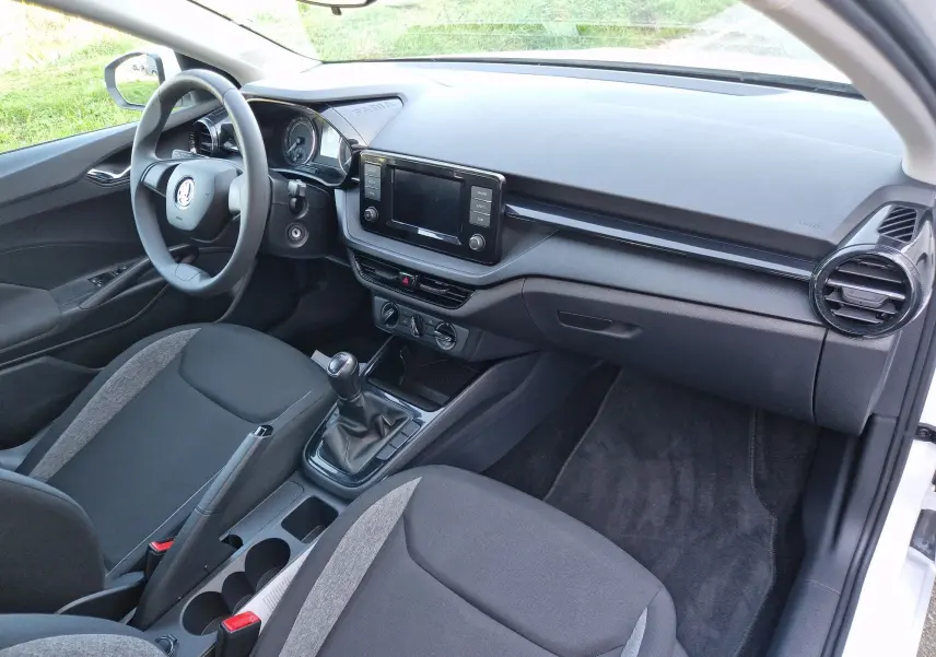 Vue intérieure côté conducteur de la Skoda Fabia Berline Active 2022, avec tableau de bord noir et levier de vitesse manuel.