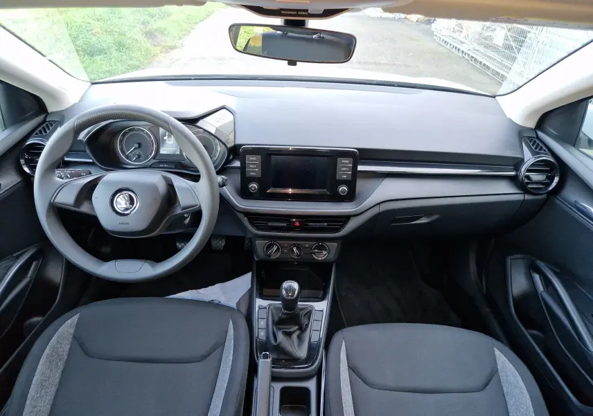 Intérieur de la Skoda Fabia Berline Active 2022 vu de face, tableau de bord noir avec écran central et volant multifonction.